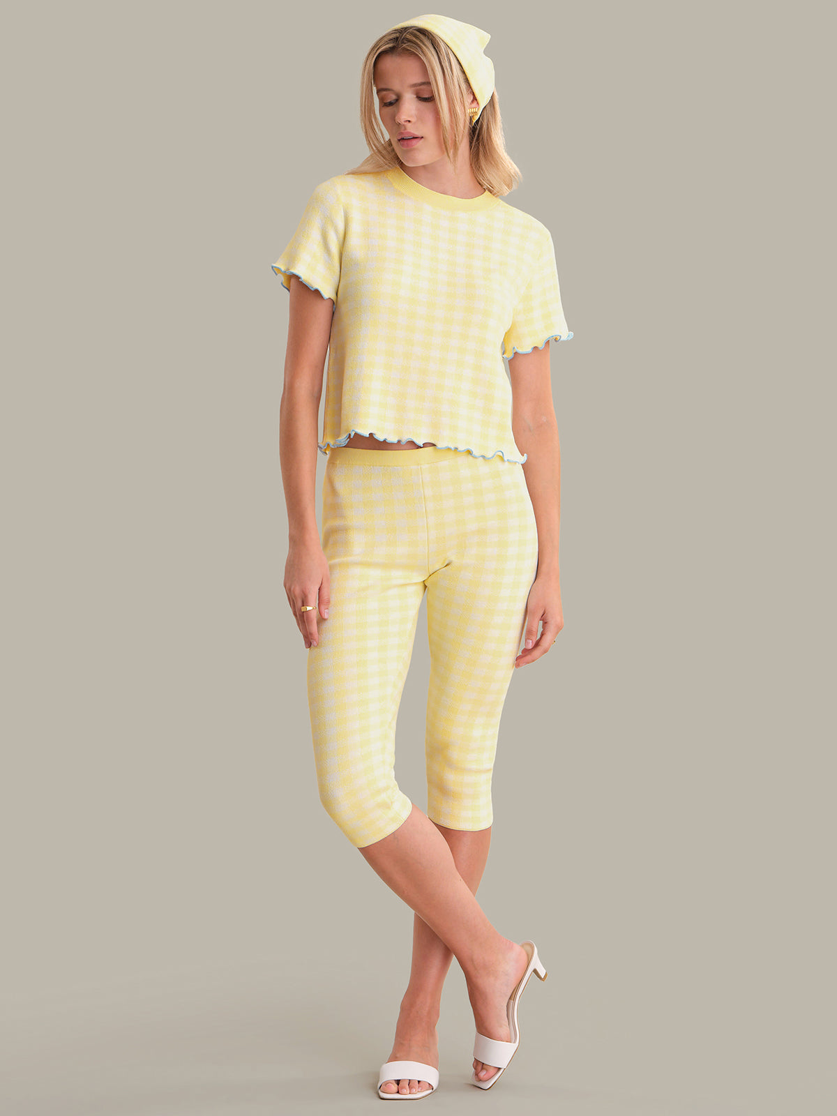 Woman wearing a yellow top with a matching headband on a gray background