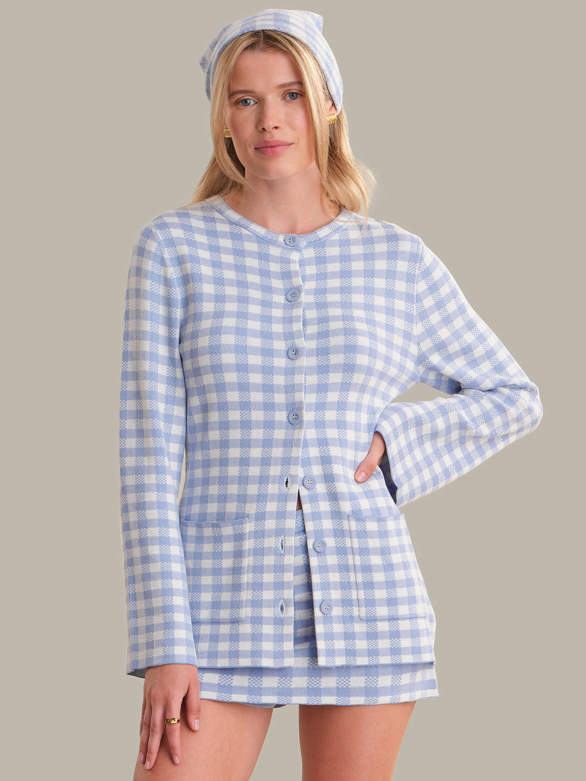 Woman wearing a blue and white checkered outfit with a matching bonnet against a gray background