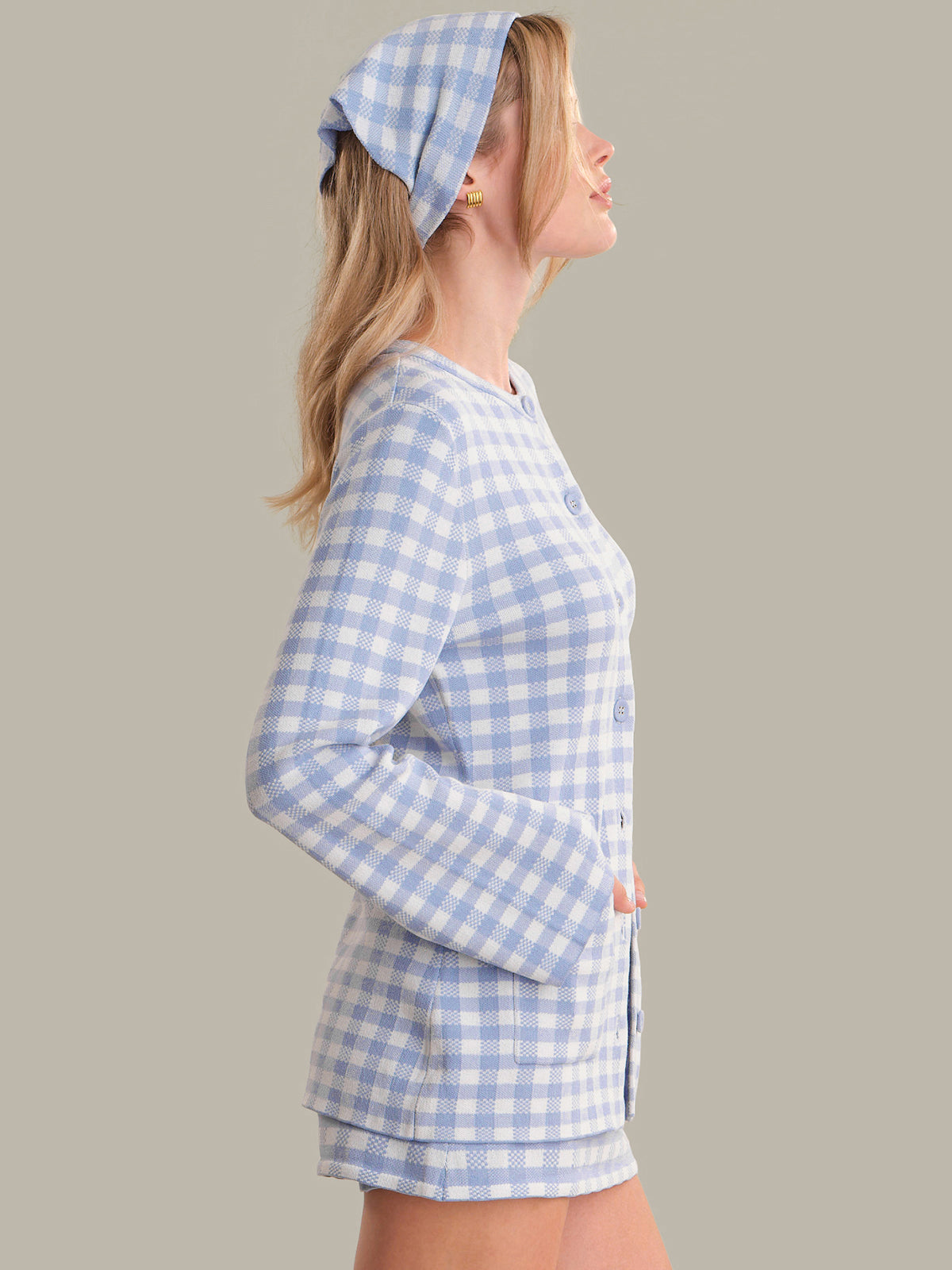 Woman wearing a blue and white checkered dress with a matching headscarf on a plain background