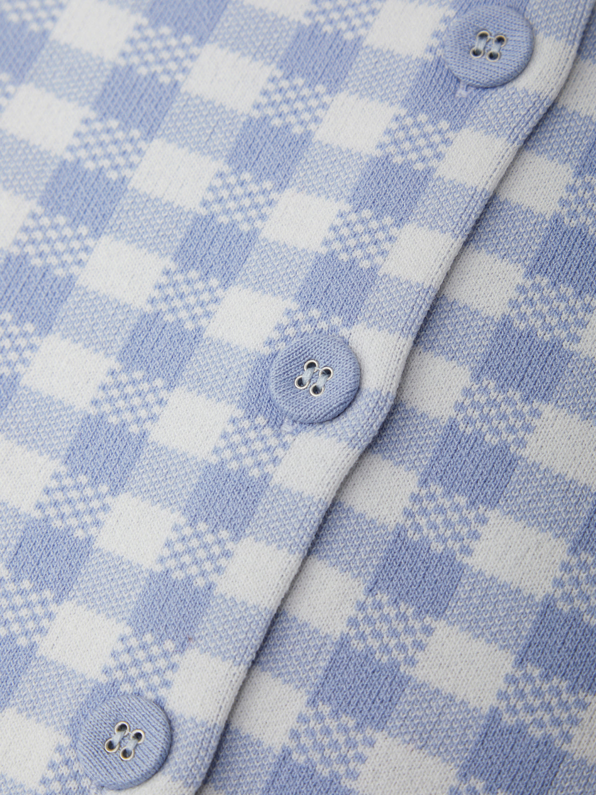 Close-up of a blue and white checkered fabric with buttons.