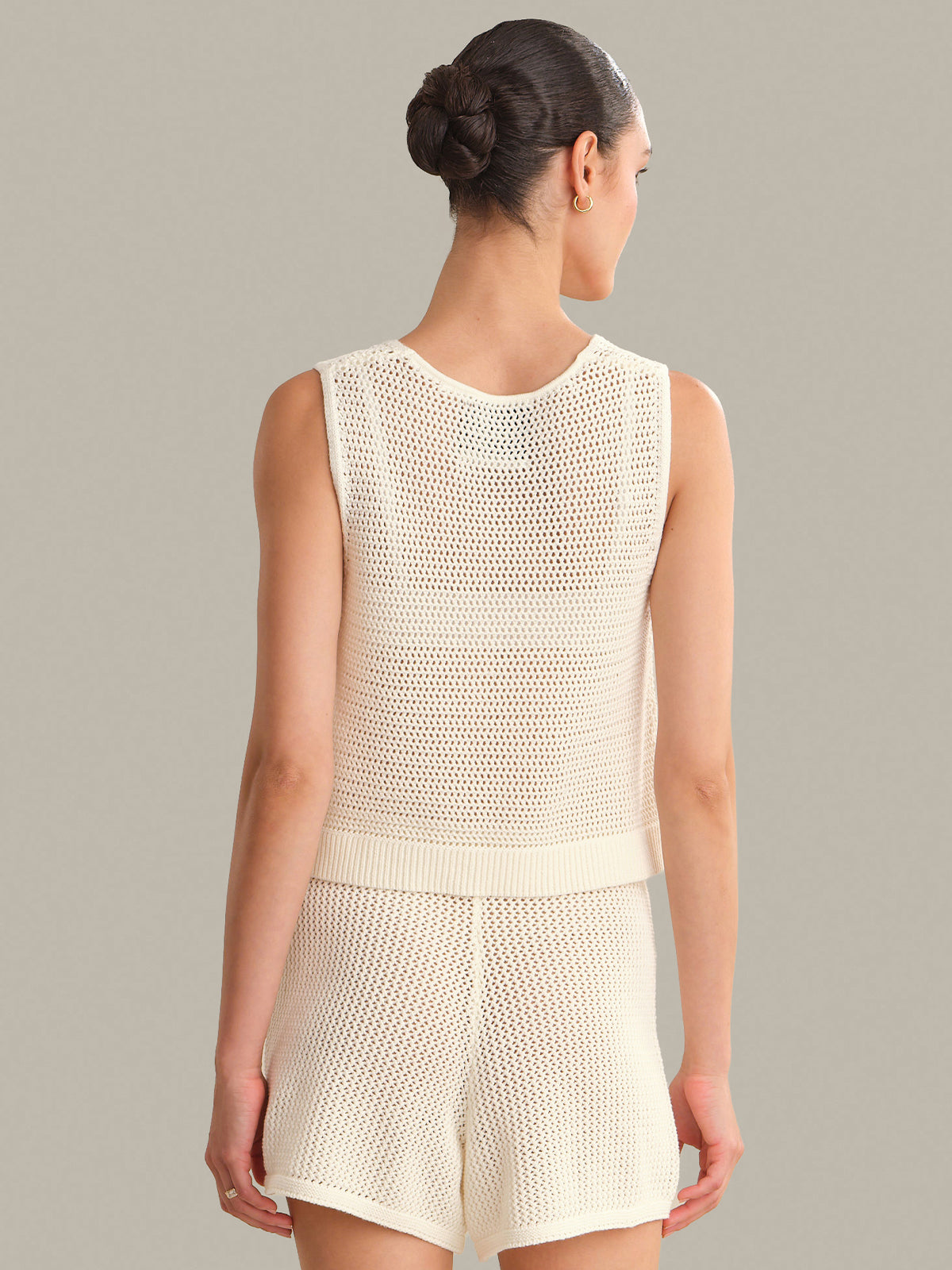 Woman wearing a cream-colored sleeveless top and shorts set against a neutral background