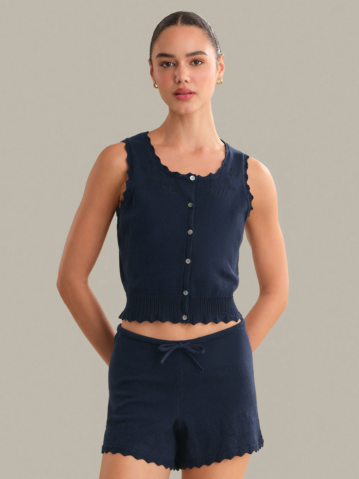 Woman wearing a navy blue sleeveless top and shorts set against a gray background