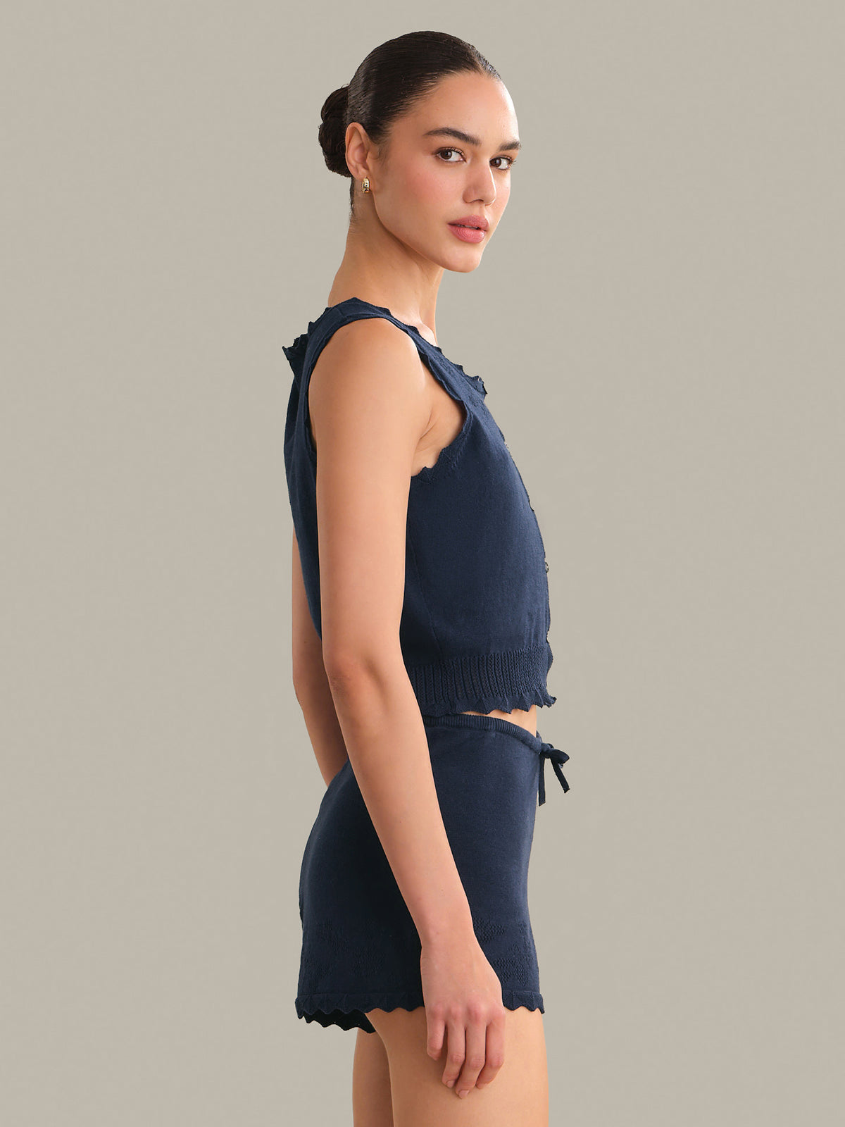 Woman wearing a navy blue sleeveless top and shorts on a gray background