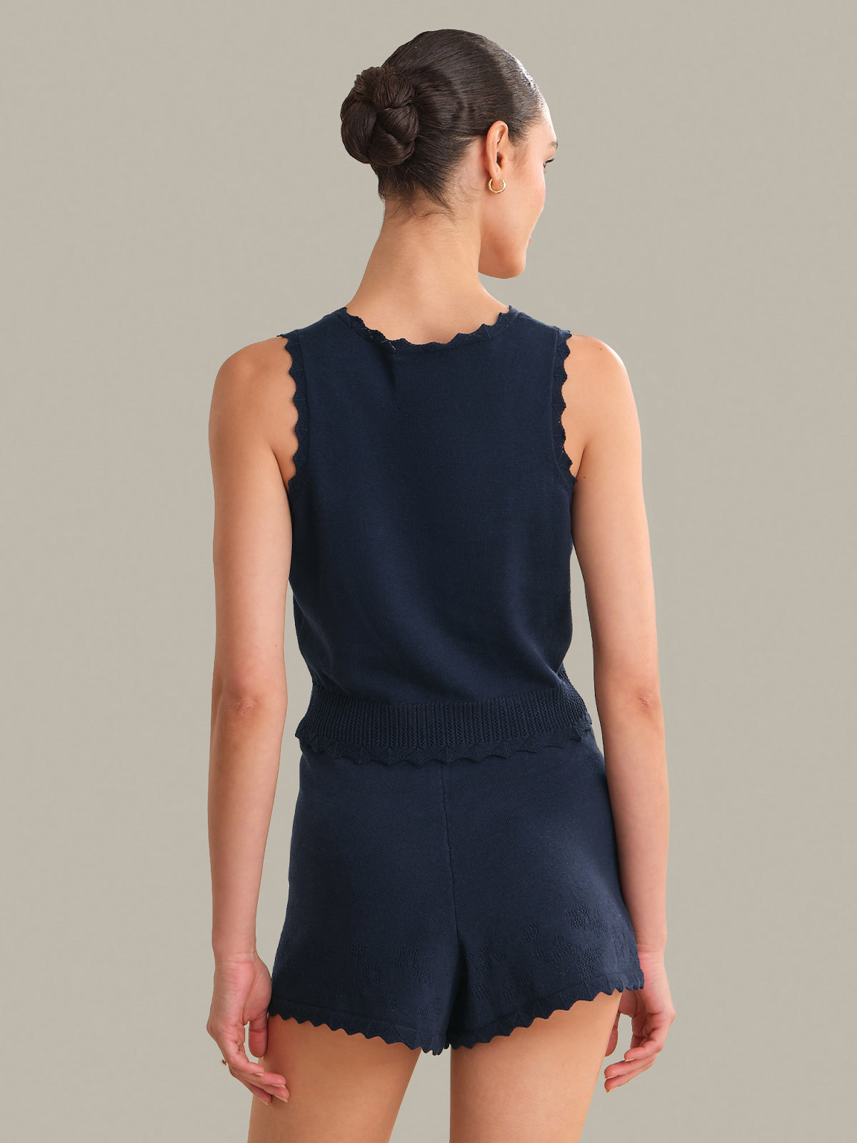Woman wearing a navy blue sleeveless top and shorts set on a neutral background