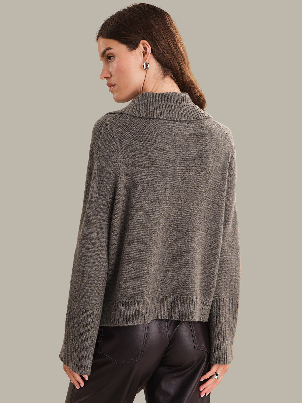 Woman wearing a gray sweater against a neutral background