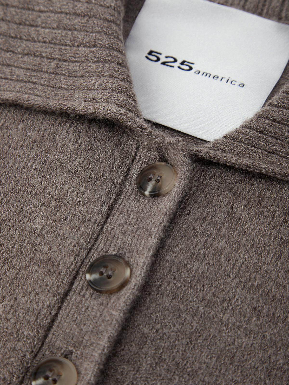 Close-up of a brown textured fabric with buttons and a visible brand label.