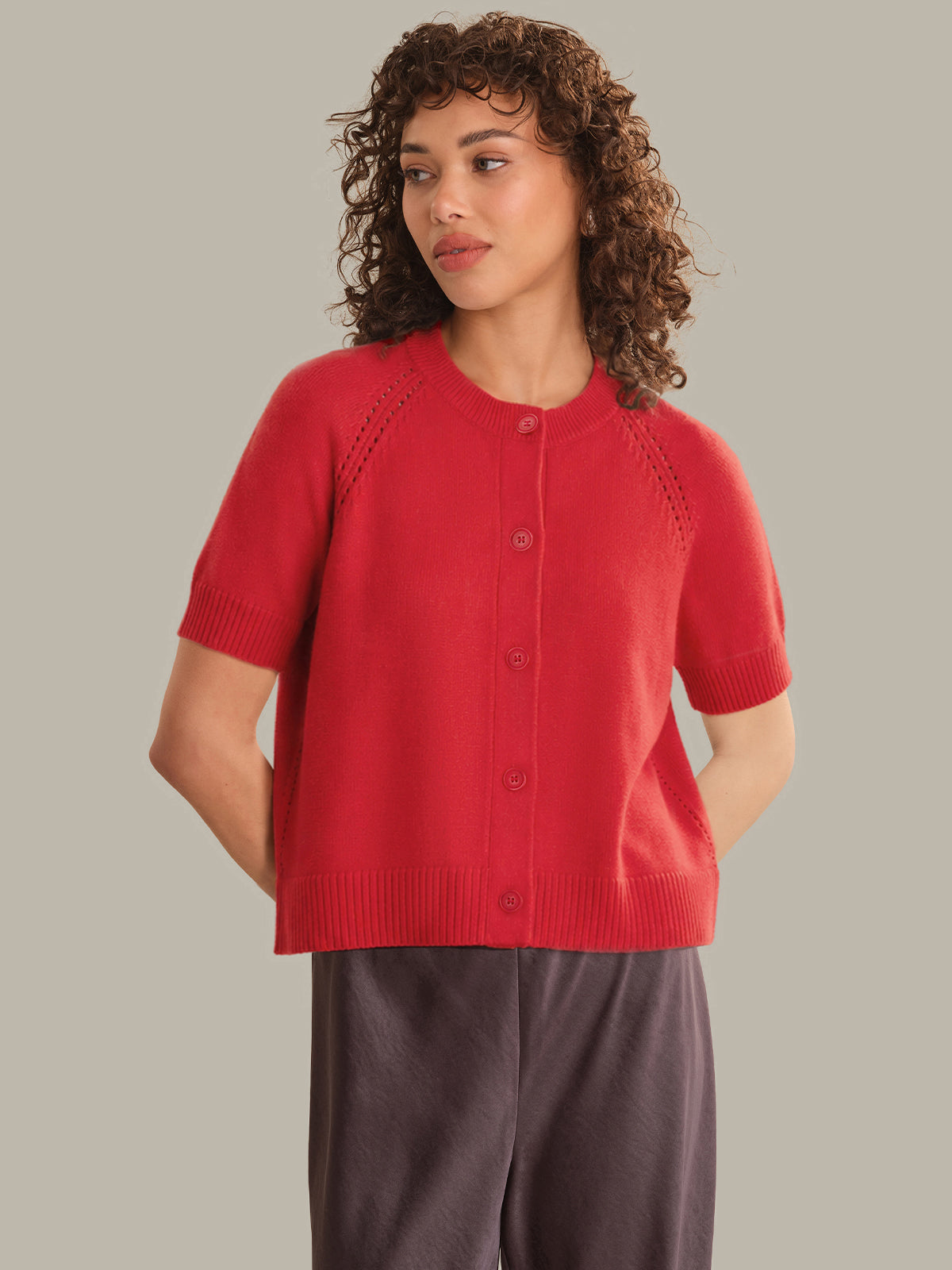 Woman wearing a red short-sleeve cardigan against a neutral background