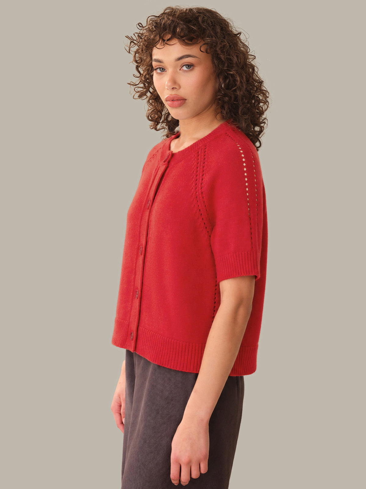 Woman wearing a red short-sleeve cardigan on a gray background