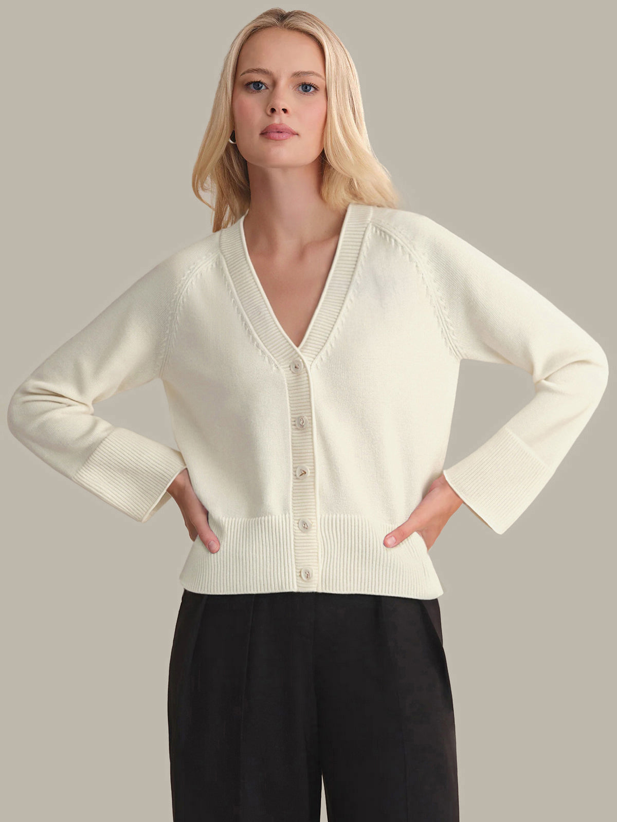 Woman wearing a cream-colored cardigan against a plain background