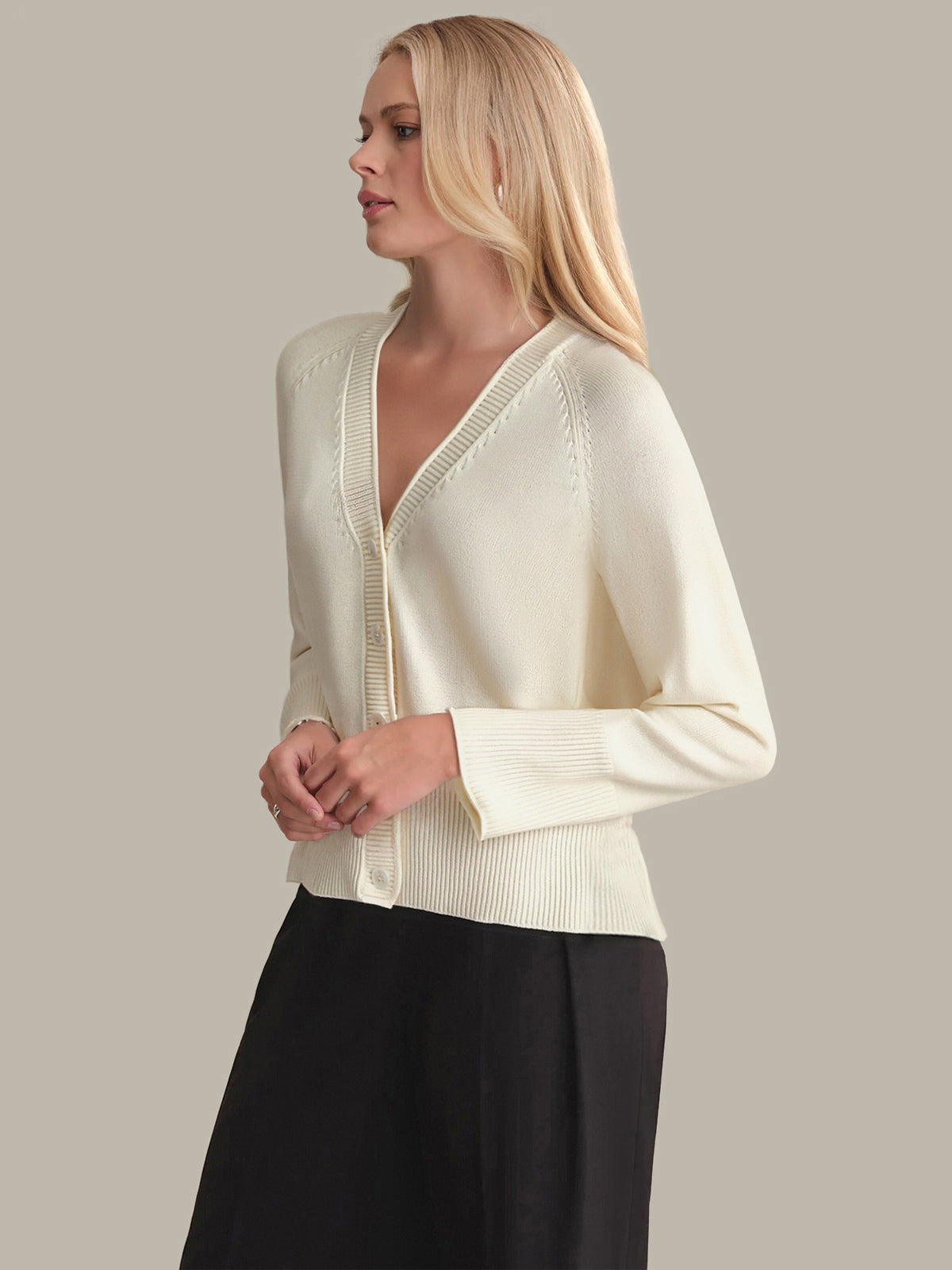 Woman wearing a cream-colored cardigan against a plain background