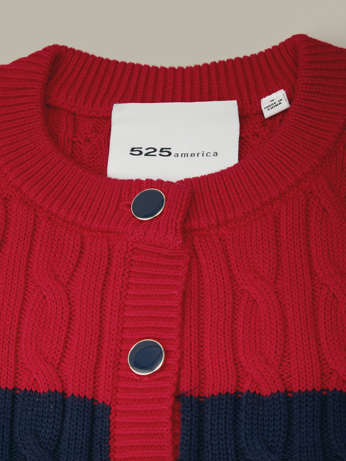 Red and navy sweater with '525 america' label on a beige background