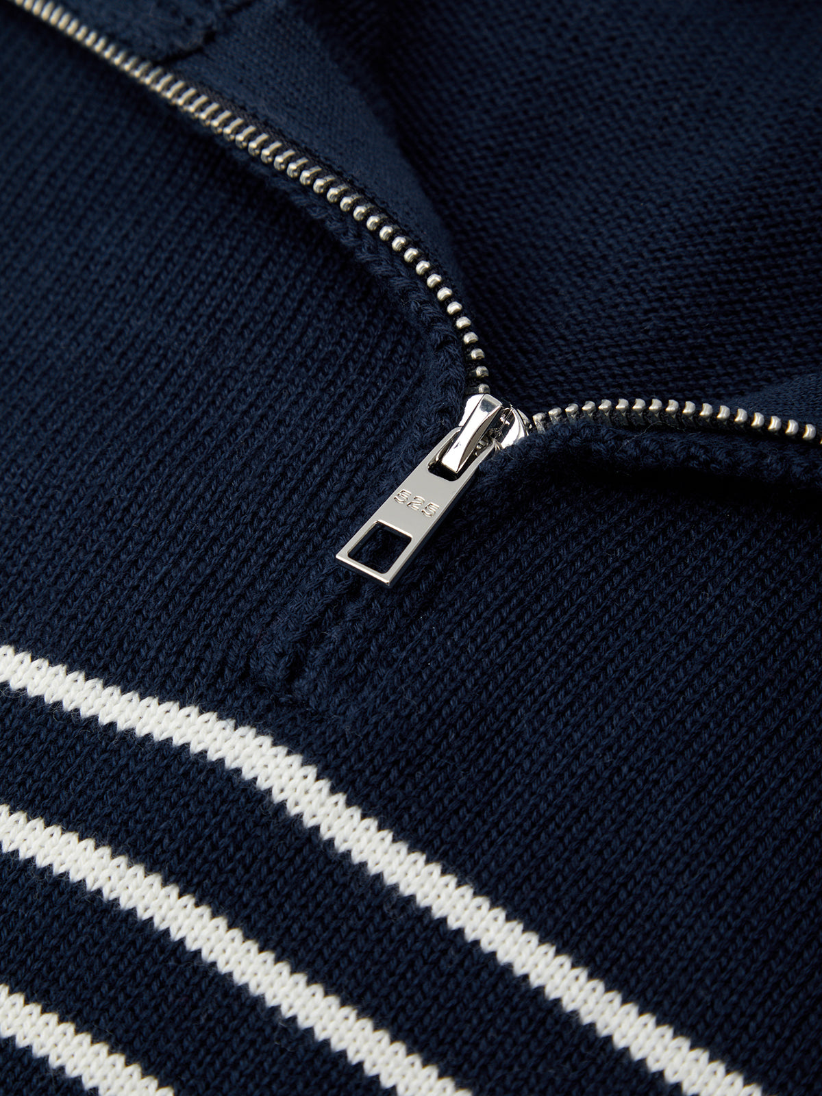 Close-up of a navy blue jacket with a silver zipper and white stripes.