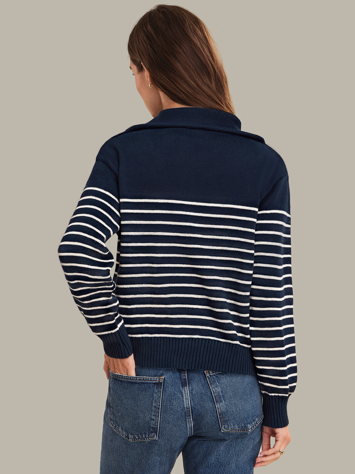 Person wearing a navy and white striped sweater with a plain background