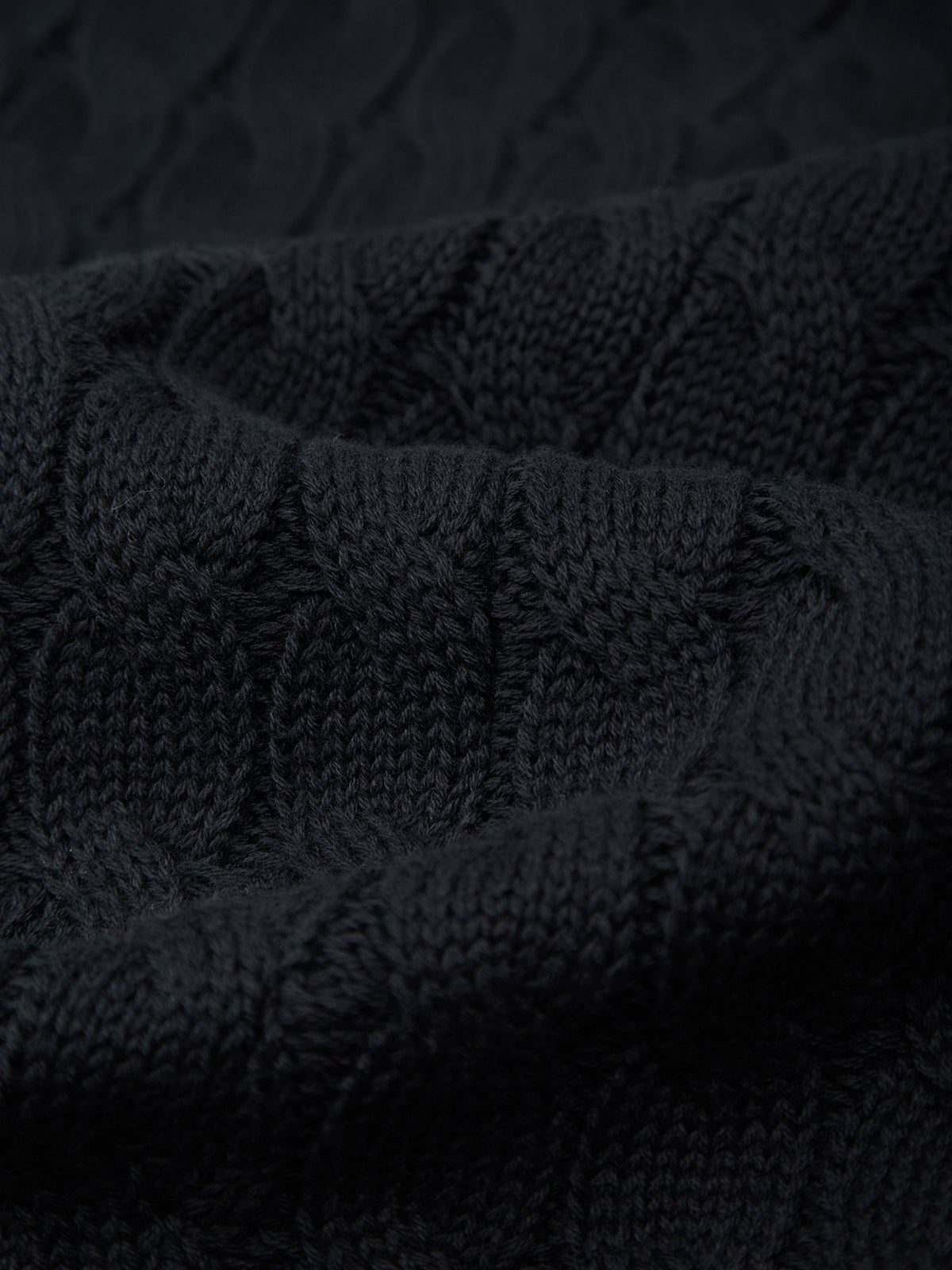 Stack of black knitted fabric with a textured pattern
