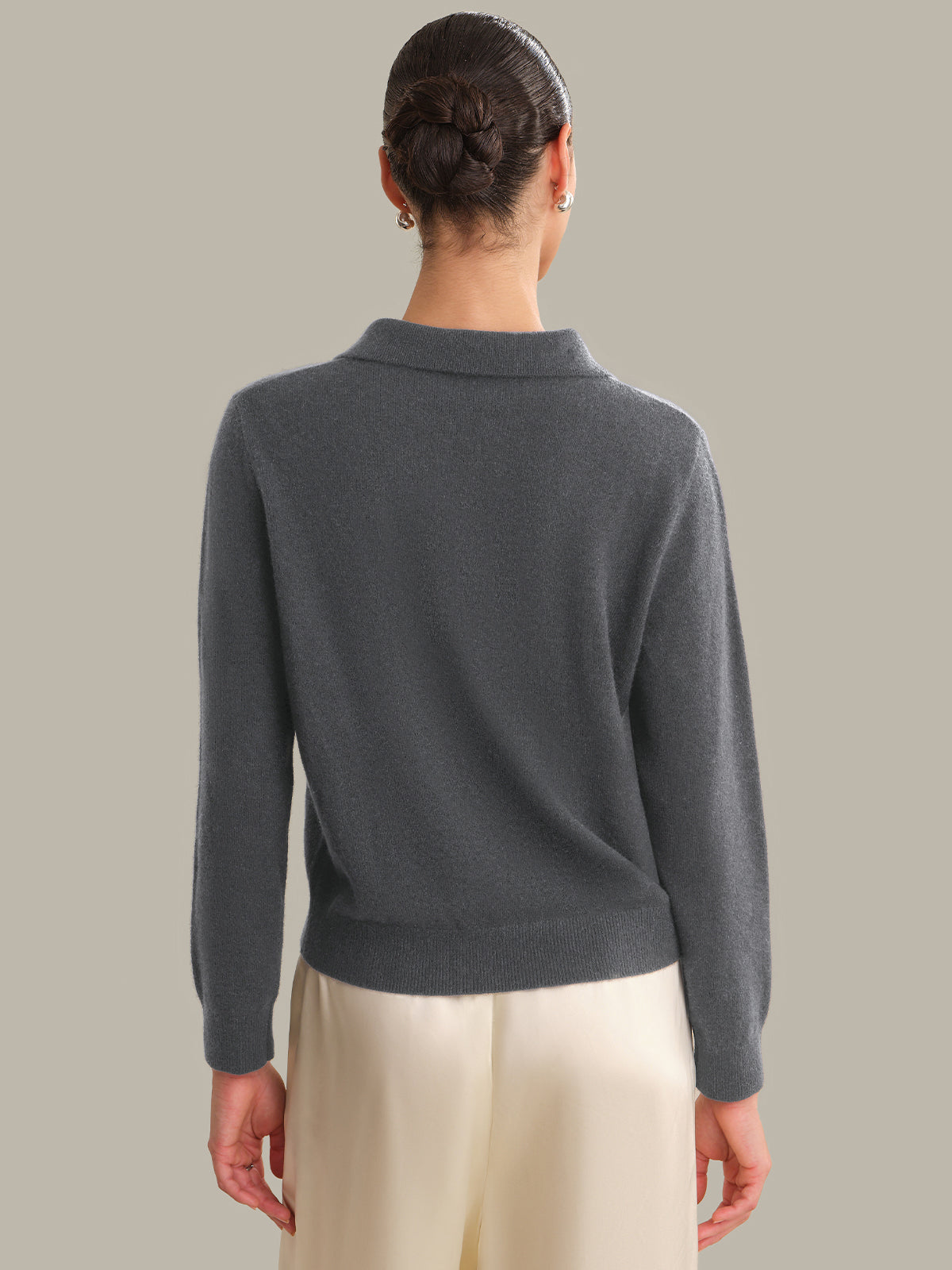 Person wearing a dark gray sweater with a plain background