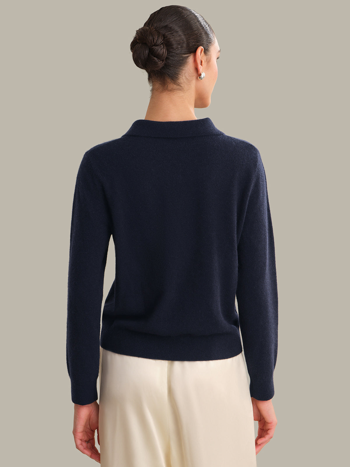 Person wearing a navy blue sweater against a neutral background