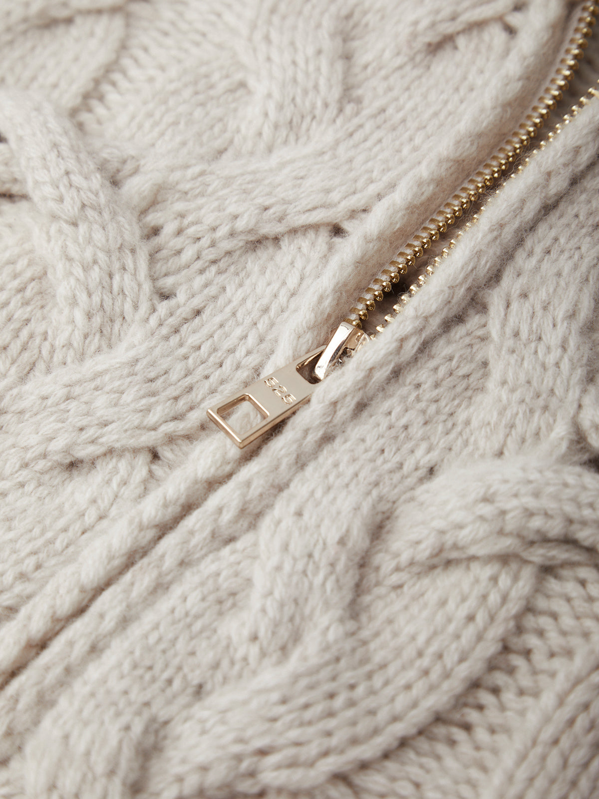 Close-up of a gold zipper on a textured beige fabric background
