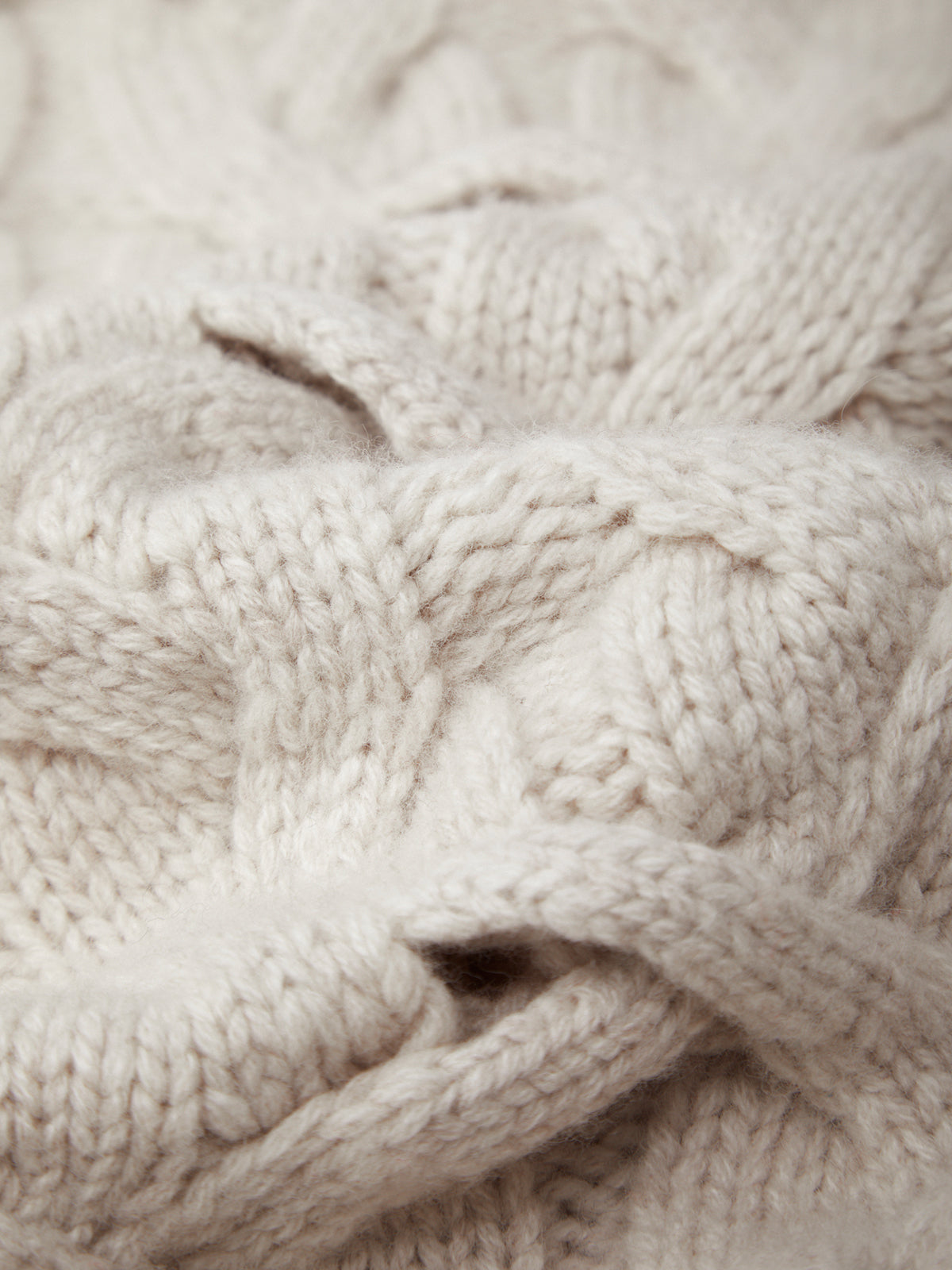 Close-up of beige knitted fabric with cable pattern