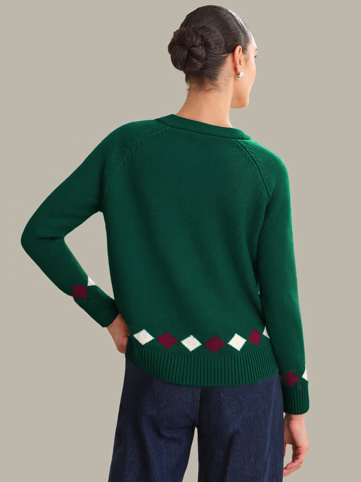 Person wearing a green sweater with a pattern on a plain background