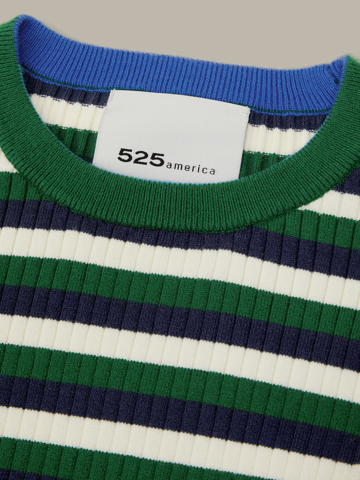 Close-up of a ribbed knit crewneck sweater with horizontal stripes in green, navy, and off-white, featuring a white neck label with the brand name '525 america'.