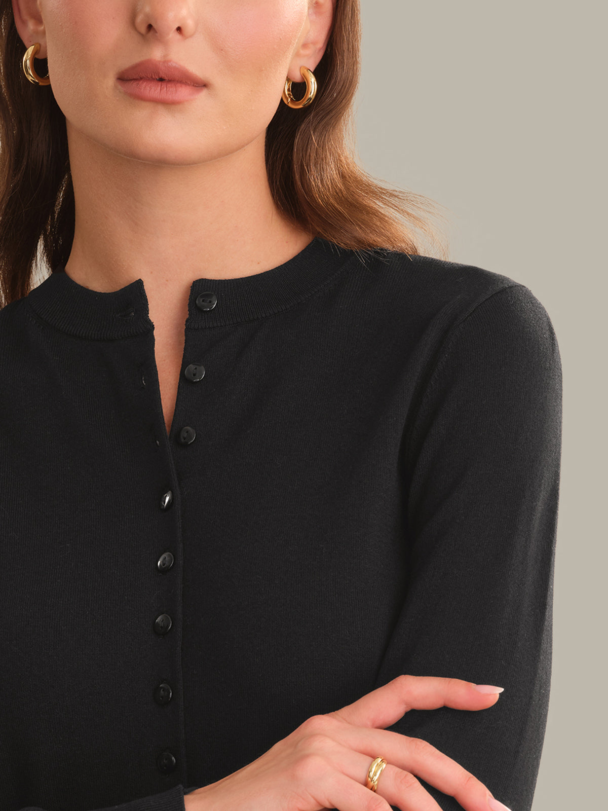 Close-up of a person wearing a black button-up shirt with a neutral background