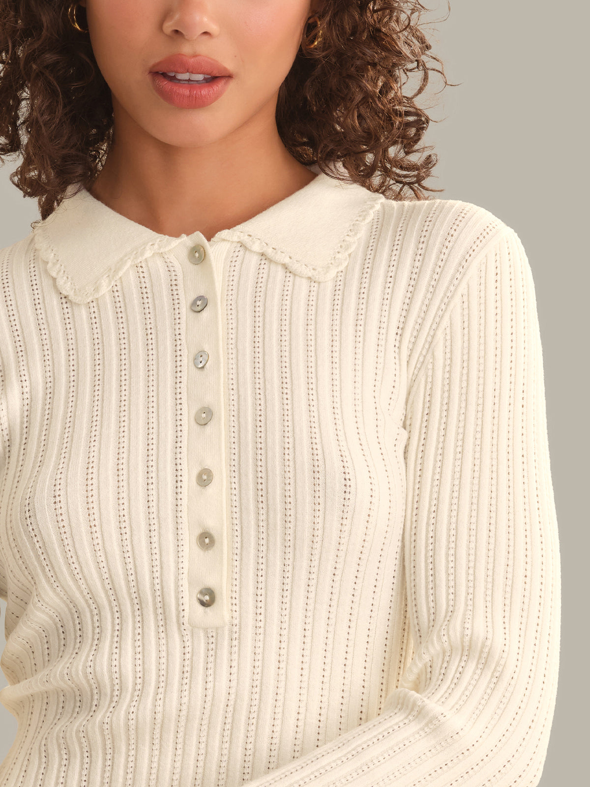 Close-up of a person wearing a textured white sweater with a collar.