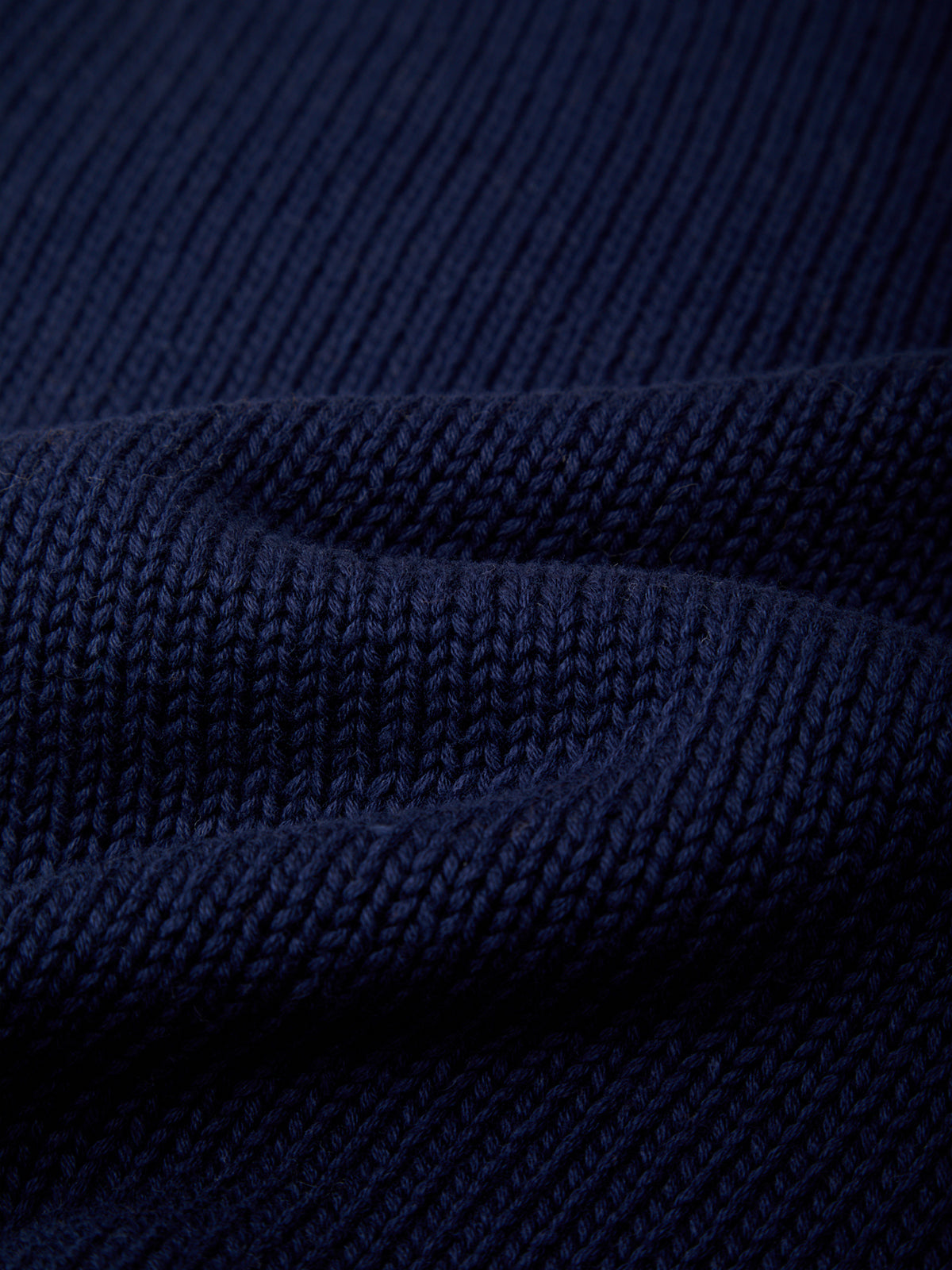 Close-up of a dark navy blue ribbed knit fabric texture with soft folds.