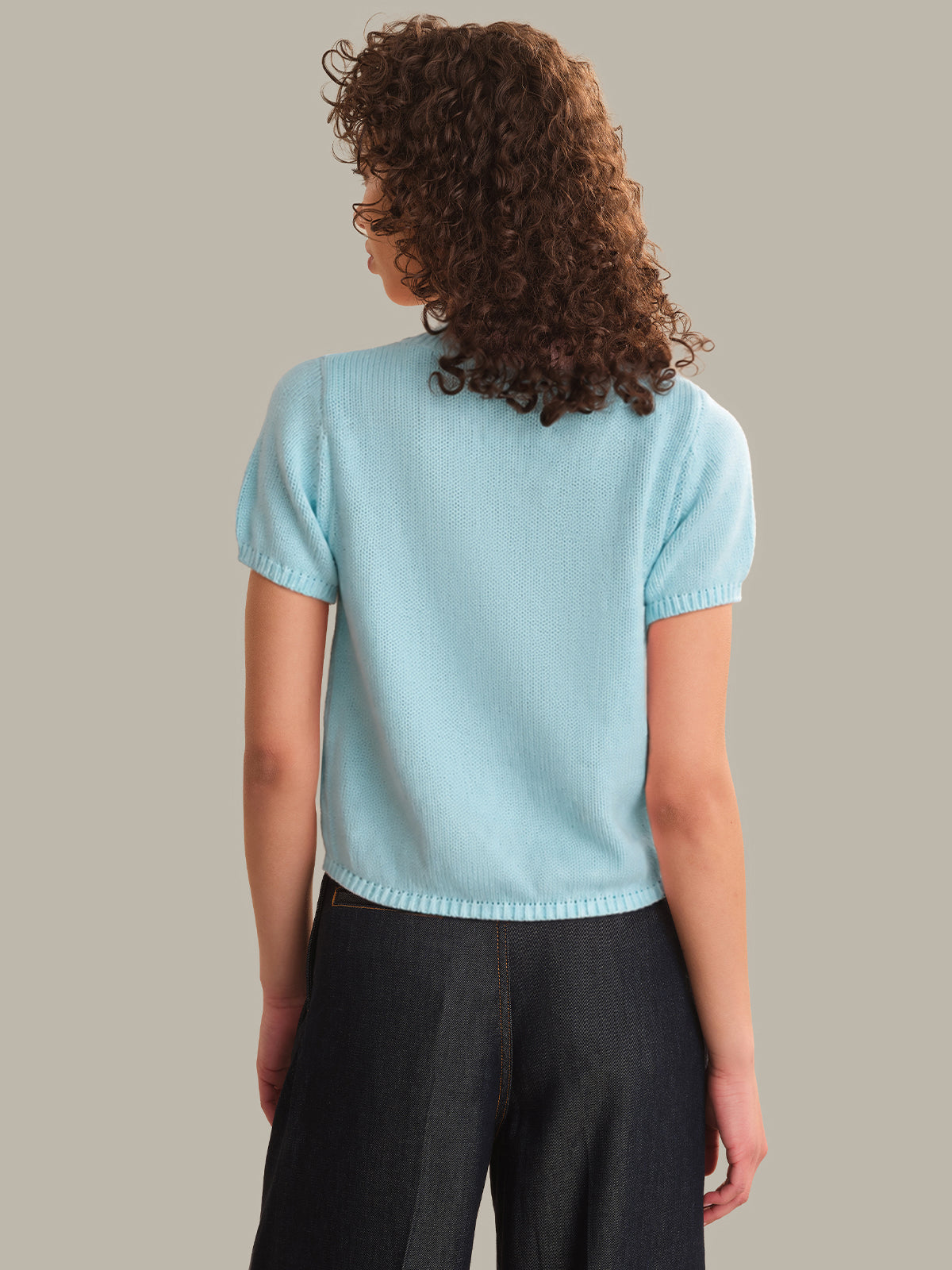 Person wearing a light blue sweater against a neutral background