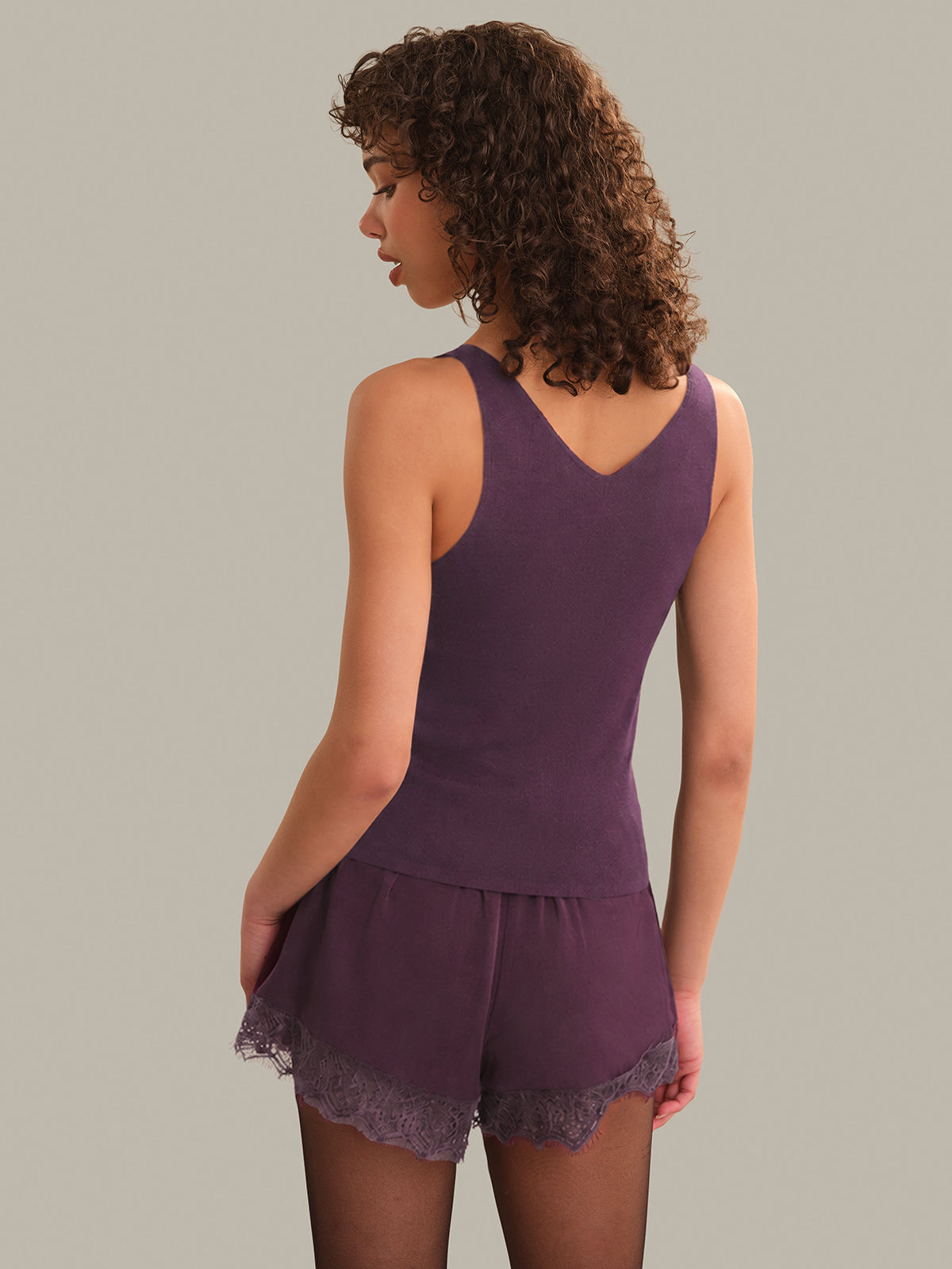 Woman wearing a purple lace-trimmed outfit on a plain background