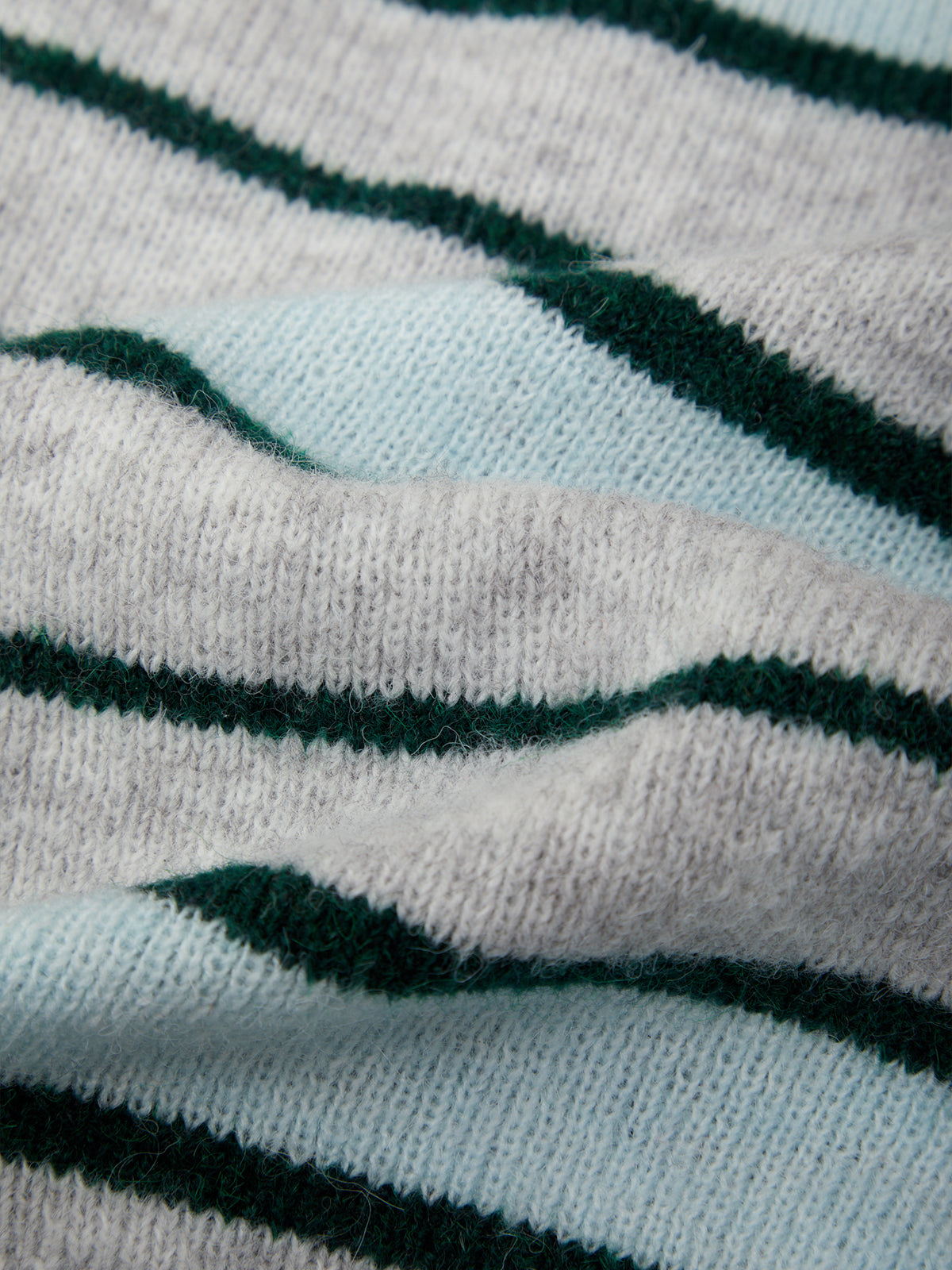 Close-up of a knitted fabric with horizontal stripes in dark green and pale blue-gray.
