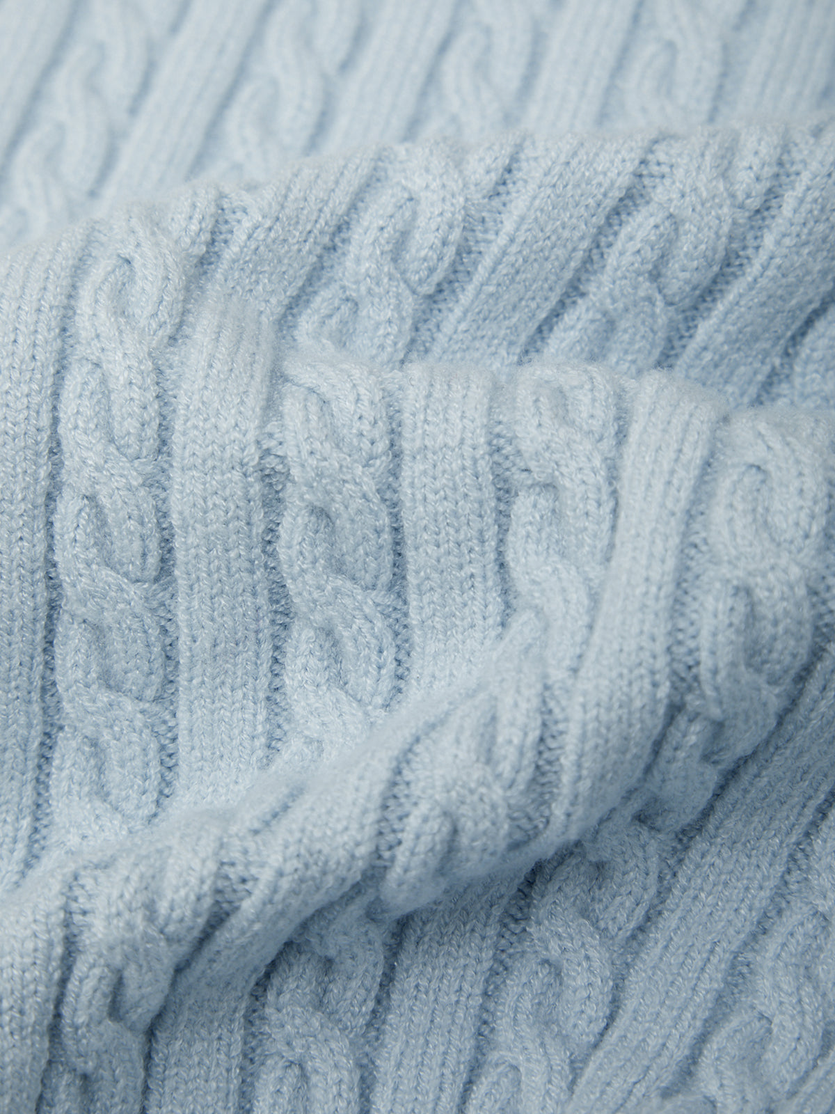 Close-up of a textured light blue fabric with cable knit pattern