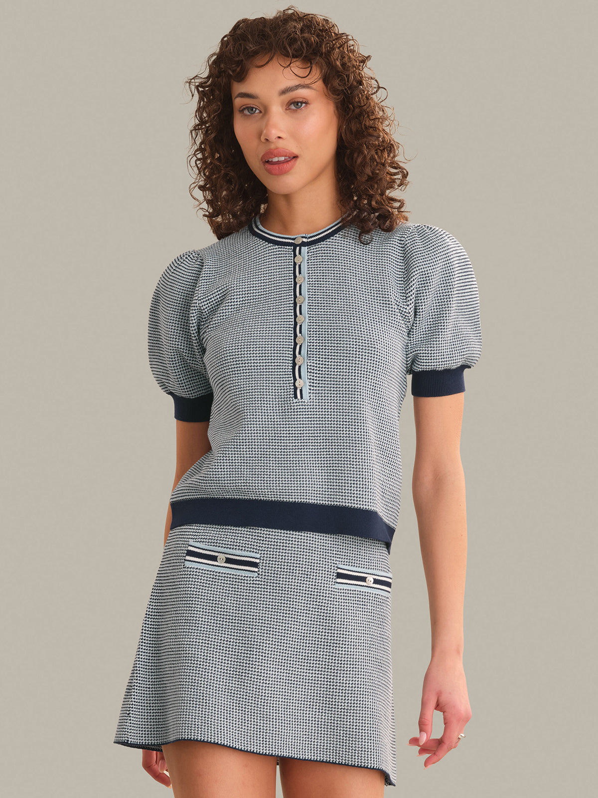 Woman wearing a blue and white checkered tops with navy accents on a gray background