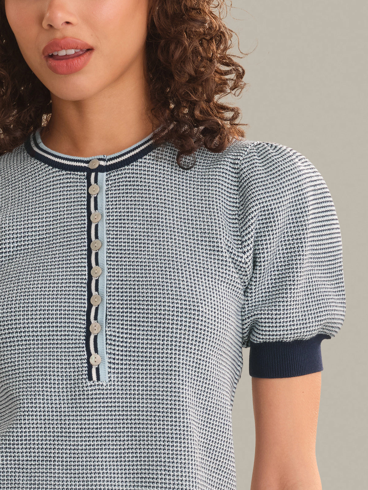 Woman wearing a patterned blouse with a neutral background