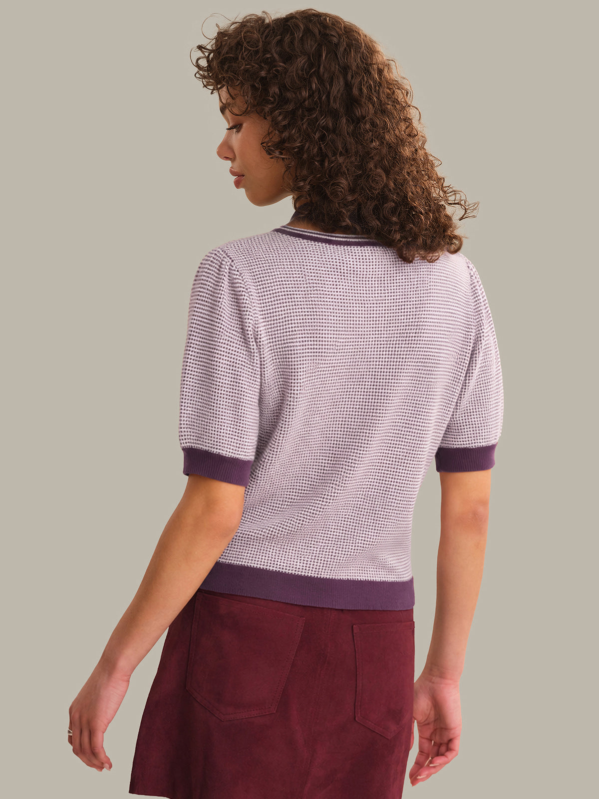 Person wearing a patterned shirt with purple accents on a plain background