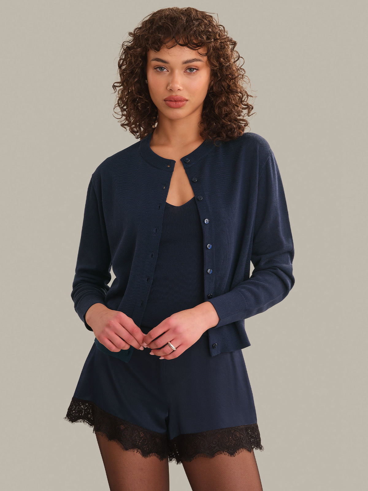 Woman wearing a navy blue cardigan and shorts set on a plain background