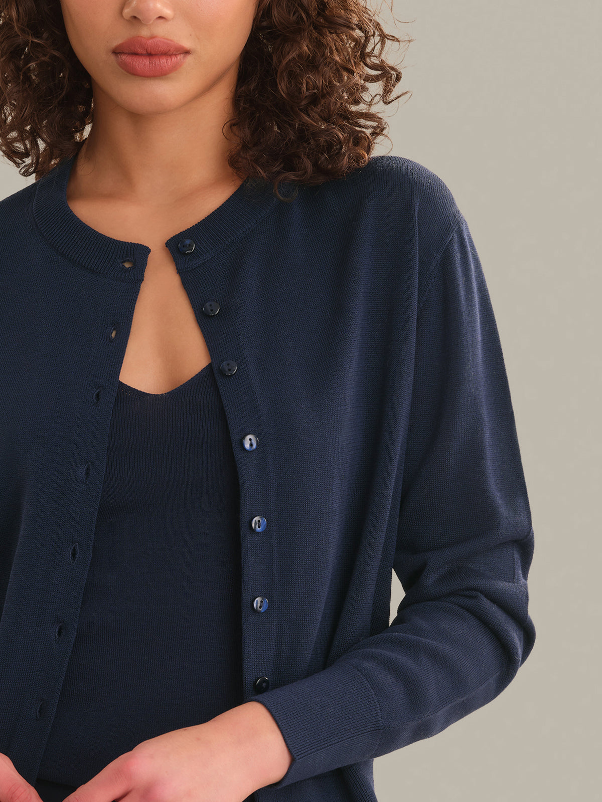 Woman wearing a navy blue cardigan against a neutral background