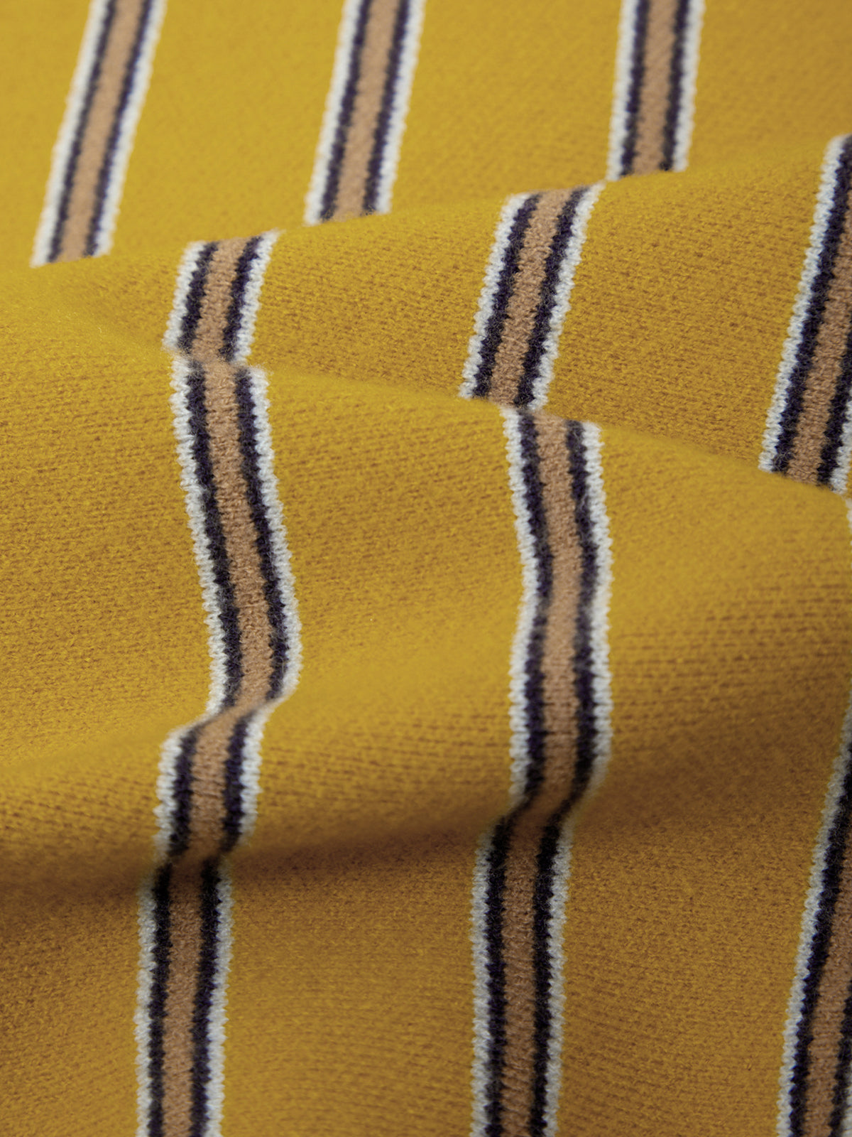A close-up of a textured knit fabric with a mustard yellow base and vertical stripes in black, white, and tan.