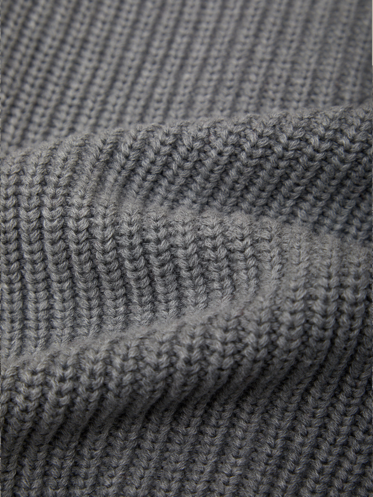 Close-up of a gray ribbed knit fabric texture, showing the detailed knit pattern and soft folds.