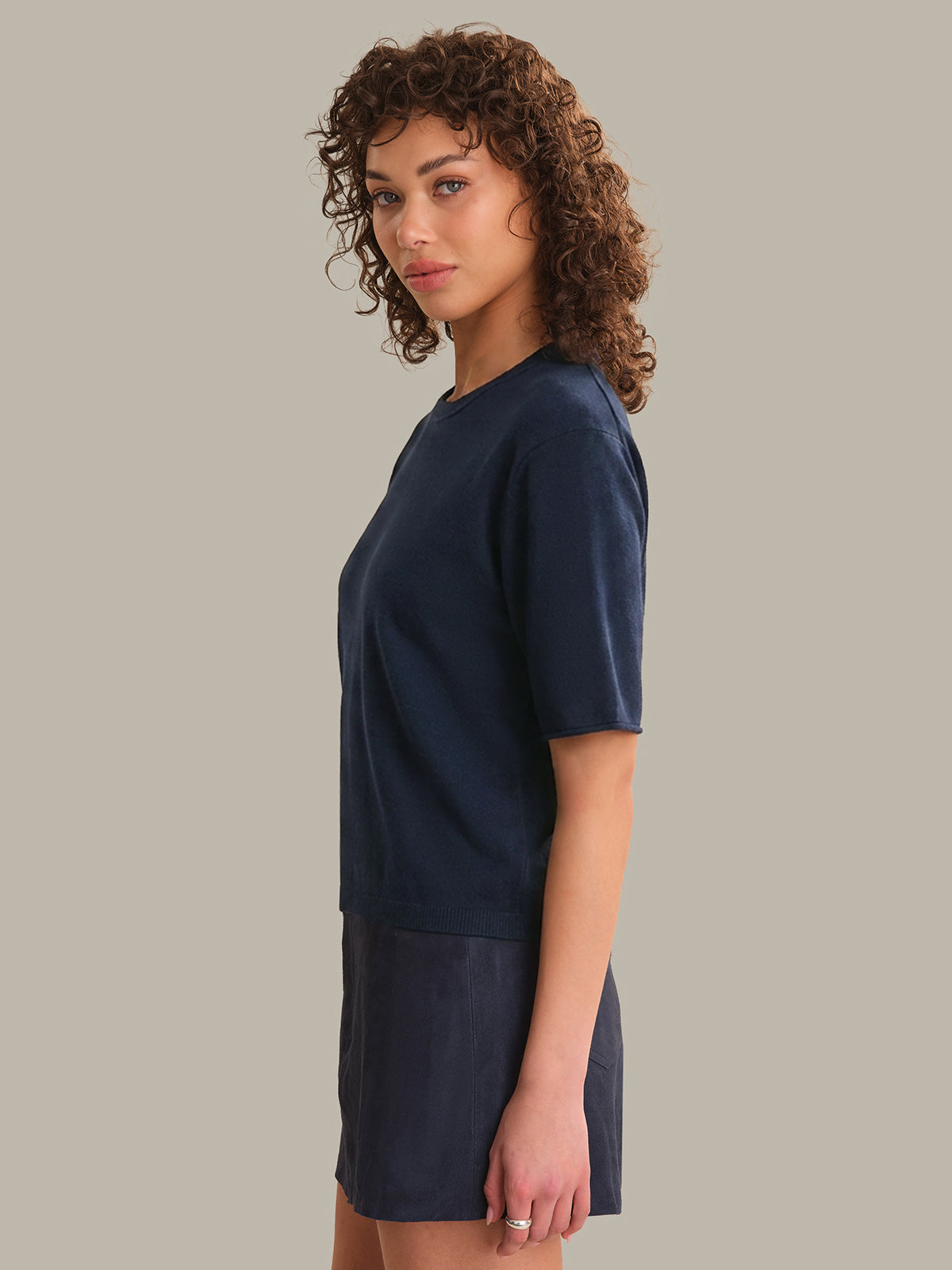 Woman wearing a navy blue top and skirt on a plain background