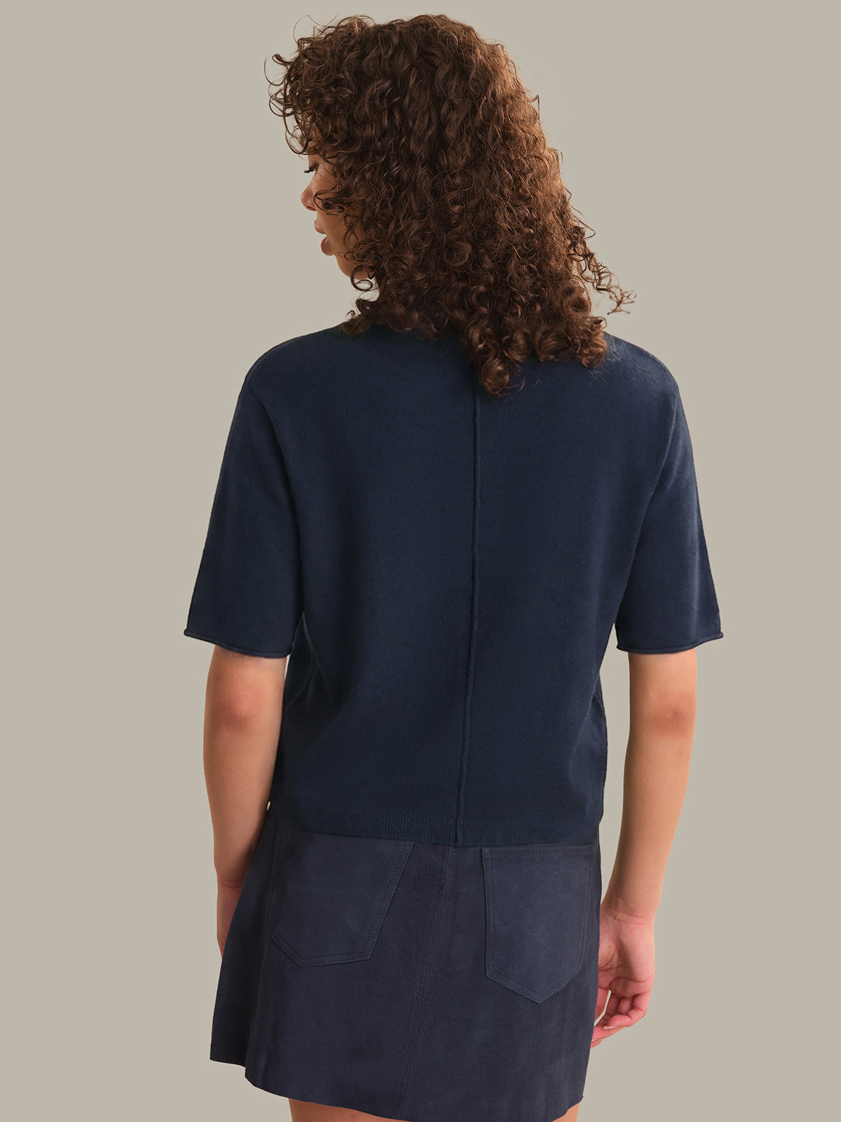 Person wearing a navy blue outfit with a plain background