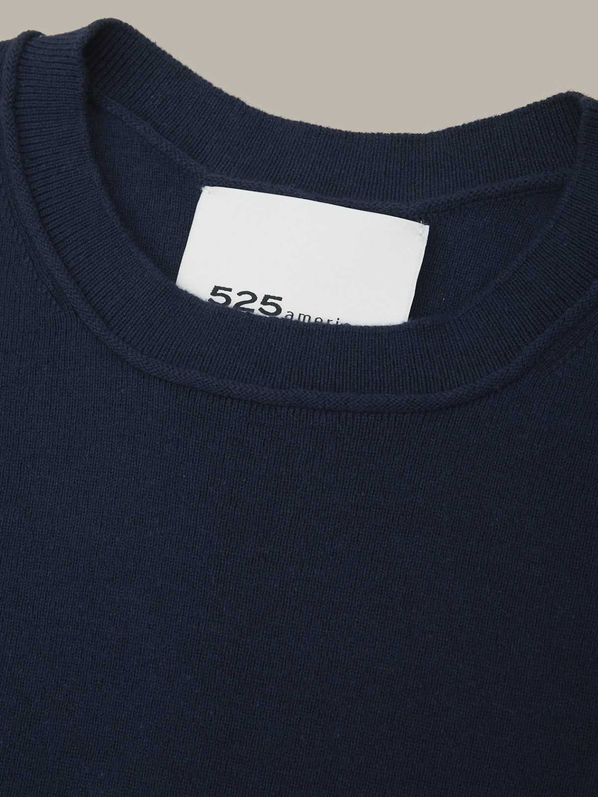 Navy blue garment with a white label displaying '525 america' on a beige background
