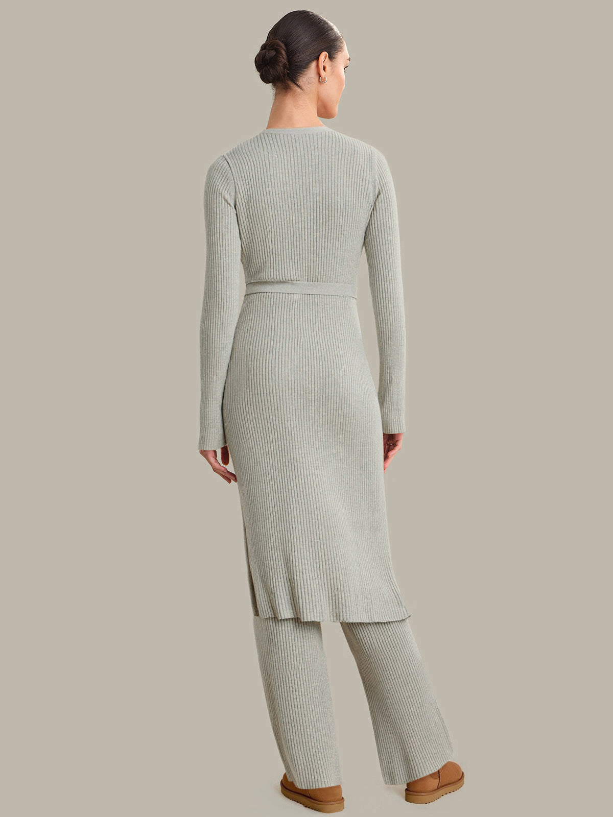 Woman wearing a light gray ribbed knit outfit on a beige background