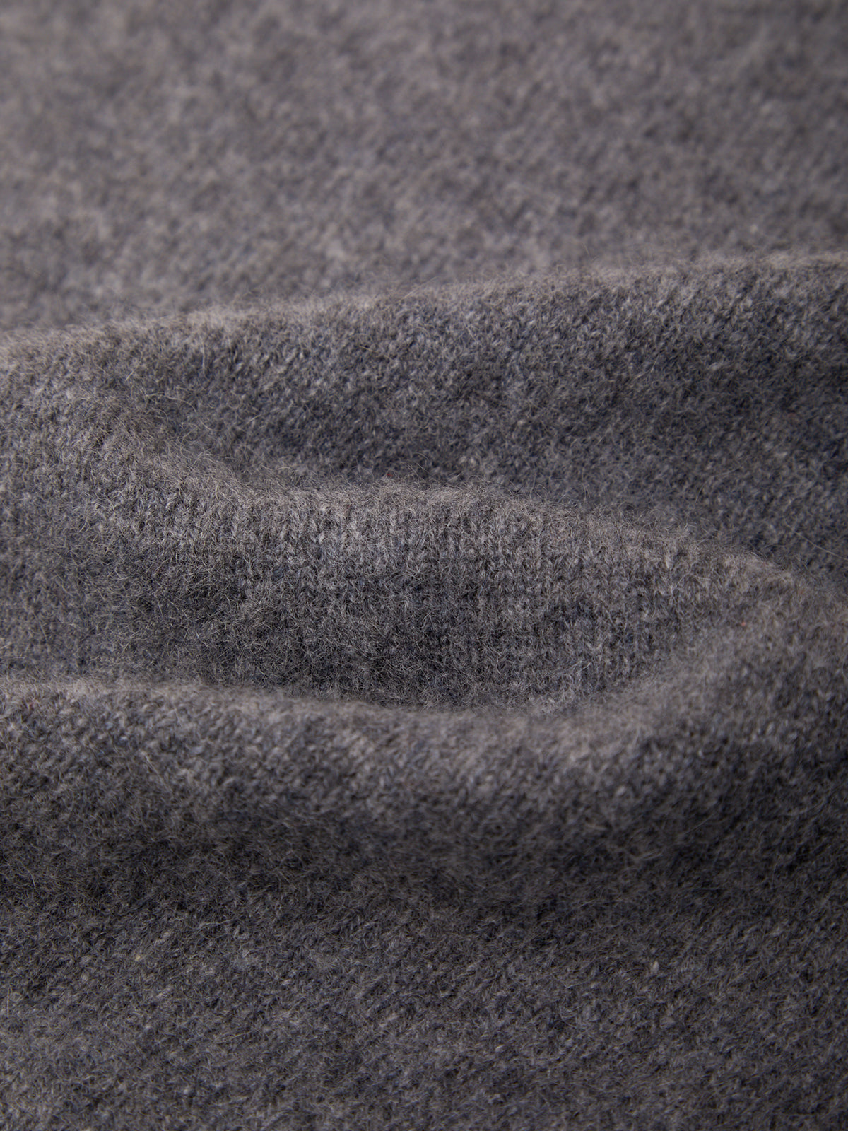 Close-up of a soft, heathered dark gray knit fabric with a fine ribbed texture and gentle folds.