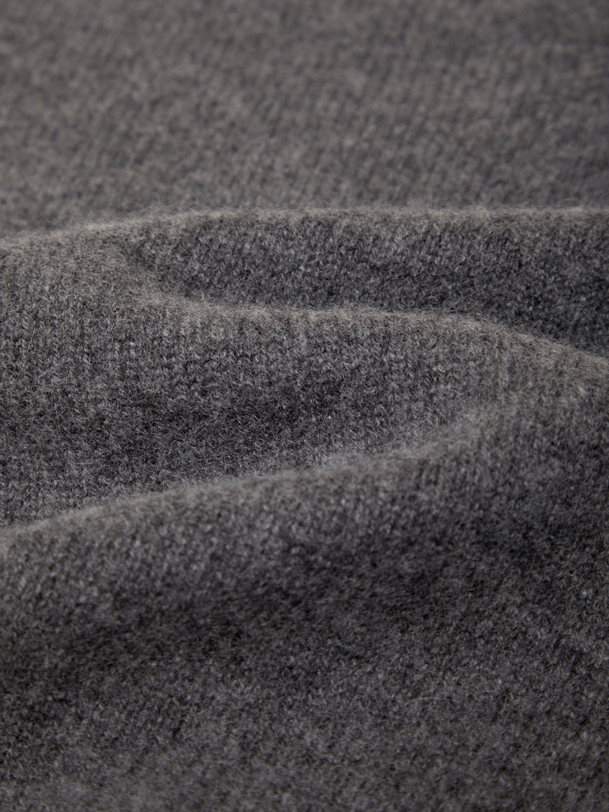 Close-up of a dark gray knit fabric with soft folds showing the texture and weave.