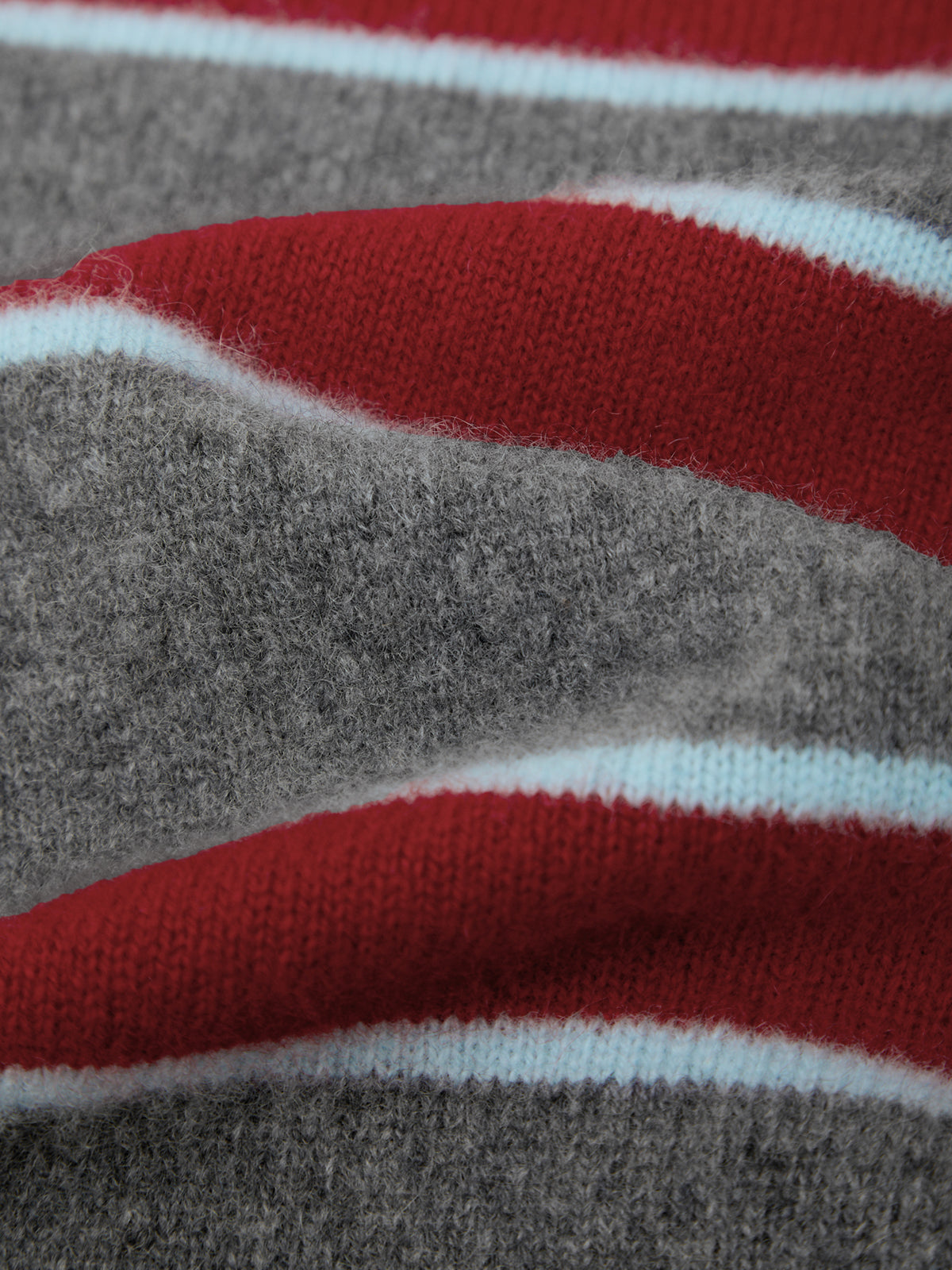 Close-up of a knit fabric with horizontal stripes in red, light blue, and heather gray.