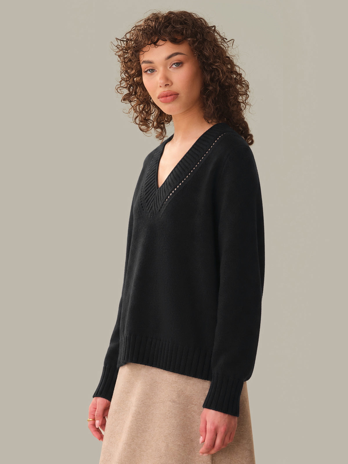 Woman wearing a black sweater against a neutral background