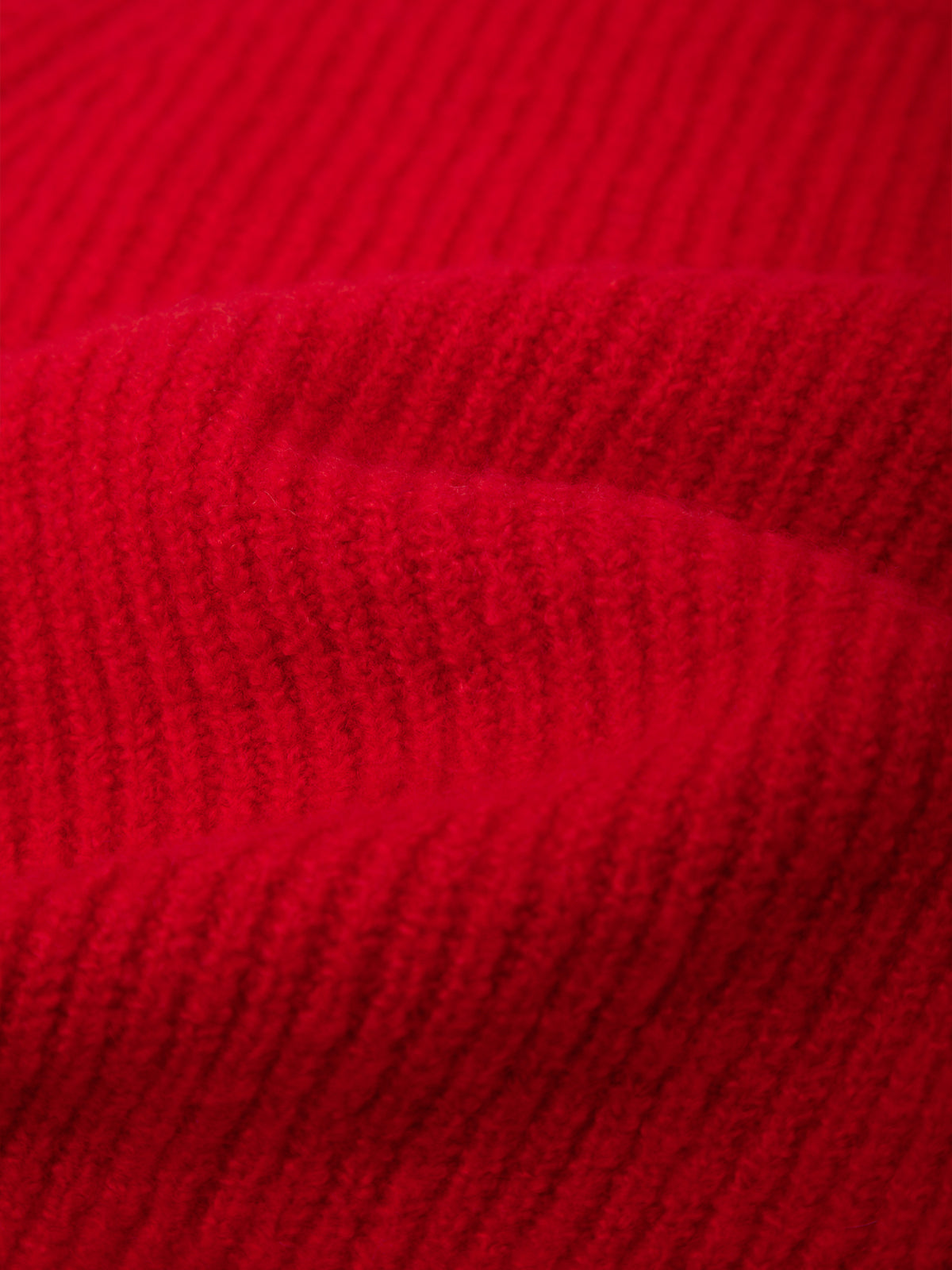 A close-up of bright red ribbed knit fabric, showing the texture and folds of the material.