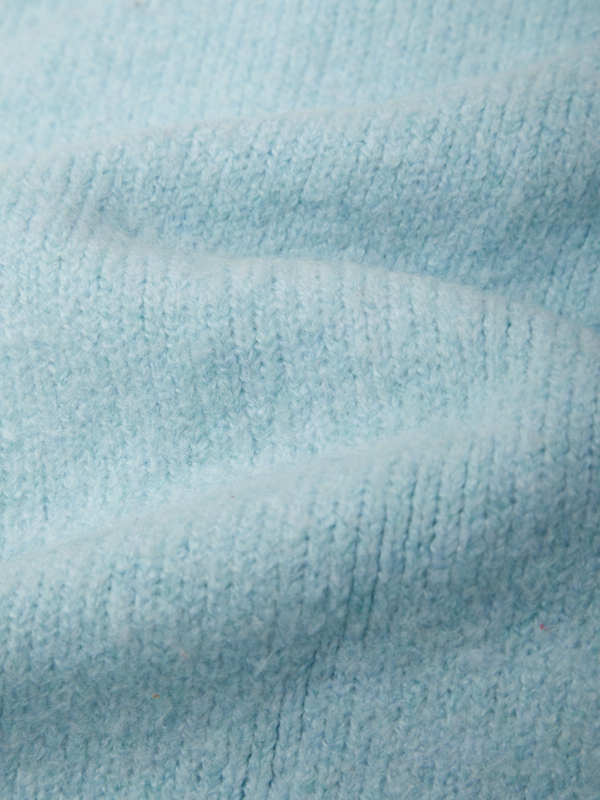 A close-up of light blue knit fabric with soft folds and visible knit texture.