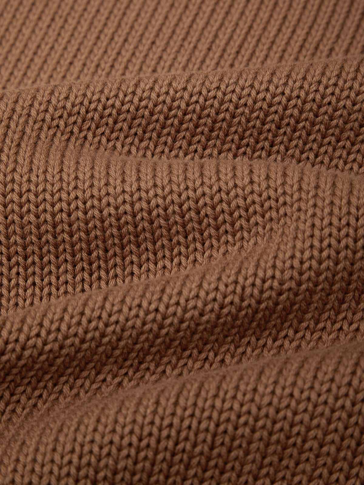 Close-up of a brown ribbed knit fabric texture, showing the detailed knit pattern and soft folds.