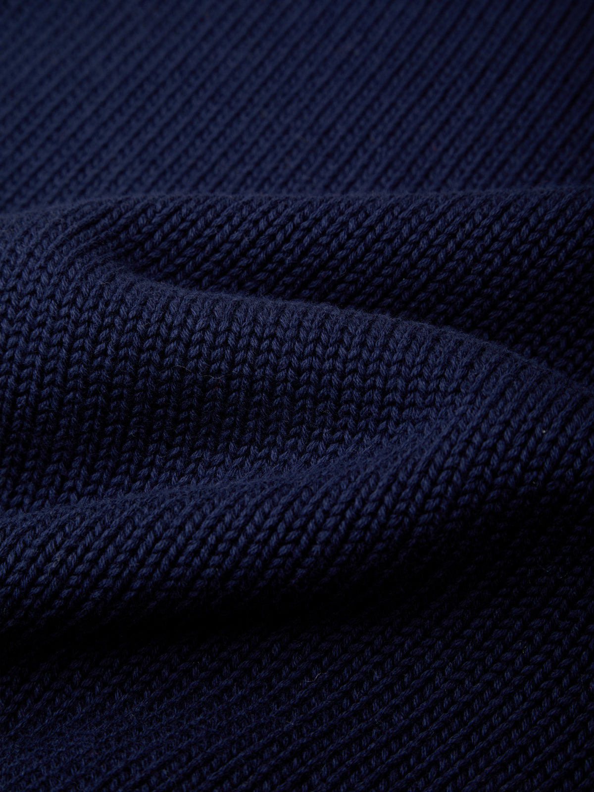 Close-up of a dark navy blue knit fabric with a ribbed texture and soft folds.